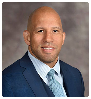 Headshot of a smiling bald man in a blue suit and tie, labeled Raphael Davis, Esq